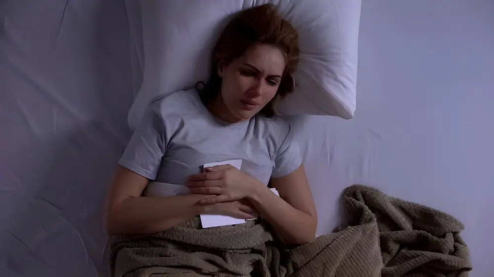 Girl lying in bed looking at torn photo of her boyfriend, hard break-up